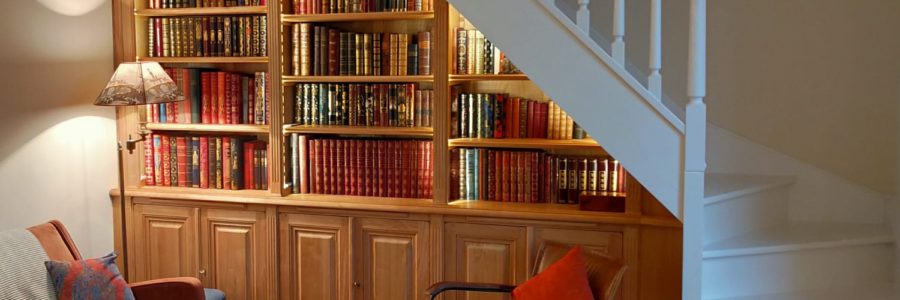 Bibliothèque intemporelle en bois naturel sous un escalier